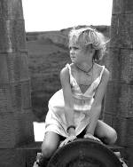 Black and white photo of a girl sitting on a cannon