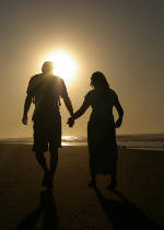 Photo of a couple walking on the beach in the morning